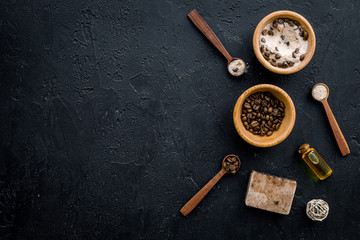 Aromatic spa cosmetics. Chocolate brown spa salt on black background top view copy space