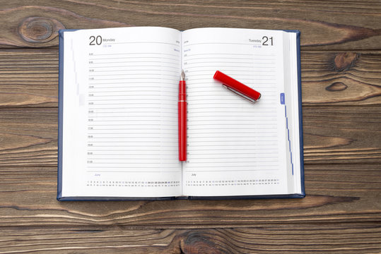 Diary, pen fountain red on a wooden background. business. finance. planning