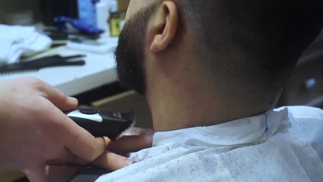 Barber shave with razor. Male barber trimming beard of client with clipper at barbershop. Close up of shaving beard man