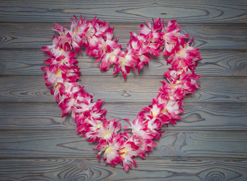 Hawaiian wreath of flowers in the shape of heart on a blue wooden background. day of lovers. Denis the saint valentine, love - Powered by Adobe