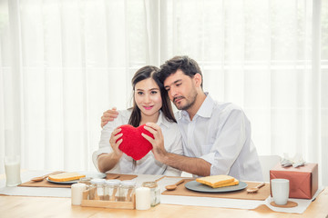 Obraz premium Happy Adult Couple with Surprise Gift in Dining Room - Lifestyle Concept