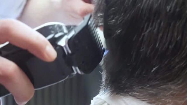 Close up barber cuts the hair of a senior man in the Barbershop