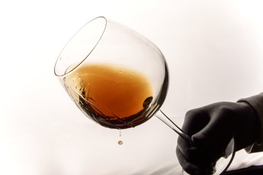 Photo of male hand with glass of a brown wine.