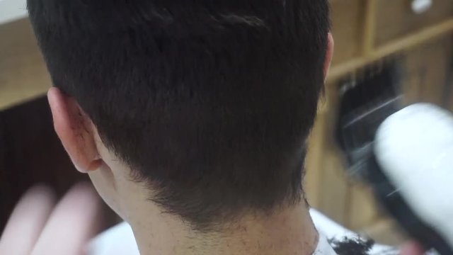 Young handsome Caucasian man getting a haircut in a modern barber shop