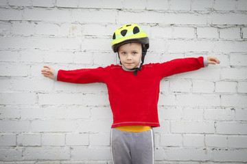 Portrait of caucasian boy in helmet with arms outstretched against white wall background