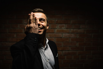 fashionable man on a black background holds his hand in the face