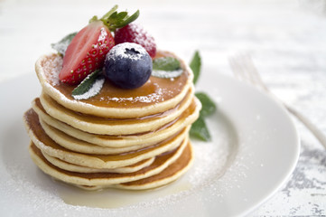 American pancakes with berries on a light background.