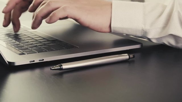 Businessman working with new modern laptop computer on wooden desk in slow motion