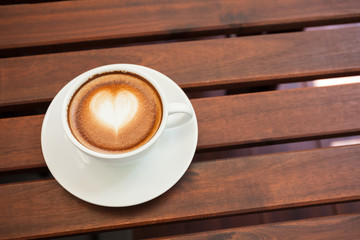 Cup of hot latte art coffee on wooden table.