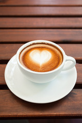 Cup of hot latte art coffee on wooden table.