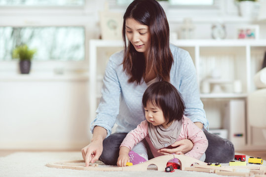 Pretty japanese woman playing with her cute laughing baby girl on the floor