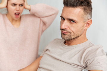 Close-up image of Confused man sitting on couch with girlfriend