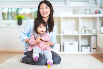Portrait of a pretty japanese mother holding her cute baby daughter