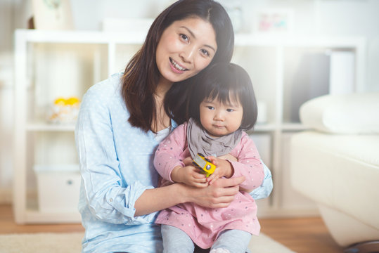 Portrait of a pretty japanese mother holding her cute baby daughter