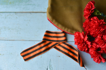 background for postcards by may 9, victory day: cap, letters, carnations and St. George ribbon