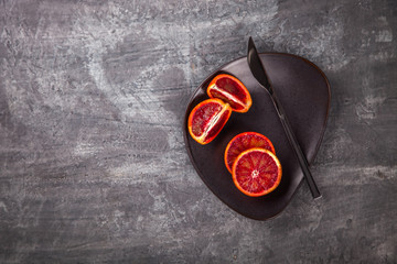  Bloody oranges cut in half on a plate with knife on a gray background.Fresh fruits. Food or Healthy diet concept.Vegetarian.Top View.Copy space for Text. selective focus..