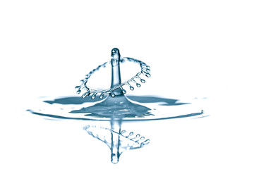 Splash and crown on rippled blue liquid or water surface . Water splash with a crown and reflection