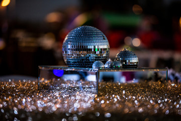 Mirrored disco balls on top of mirrored platform surrounded by glitter and jewels as centerpiece on...