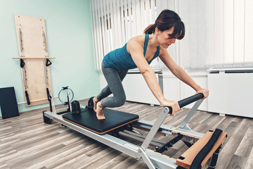Fototapeta premium Woman exercising on pilates reformer