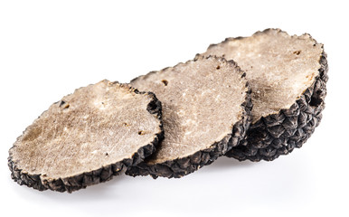 Slices of black summer truffle on a white background.