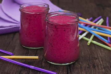 Berry smoothies and purple napkin in glass bowls.