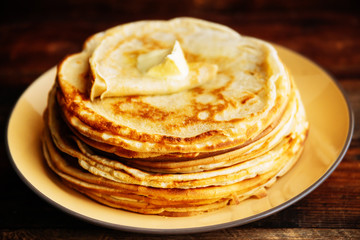 Russian Maslenitsa, Shrovetide, pancake week, carnival, shrove, pancake day. a stack of pancakes with butter upstairs on plate, on wooden background, close-up
