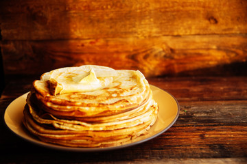 Russian Maslenitsa, Shrovetide, pancake week, carnival, shrove, pancake day. a stack of pancakes with butter upstairs on plate, on wooden background, close-up