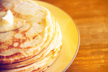 Russian Maslenitsa, Shrovetide, pancake week, carnival, shrove, pancake day. a stack of pancakes with butter upstairs on plate, on wooden background, close-up