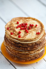 High stack of classic Russian thin pancakes with red currant berries . Rustic style. Traditional for the Russian pancake week Maslenitsa 