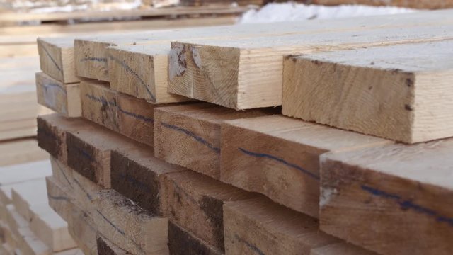 Stacks of processed  packed lumber plank lying in yard of woodwork production on sunny winter day