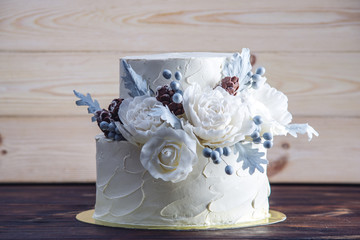 Delicate white bunk wedding cake decorated with an original design using mastic roses. Concept of...