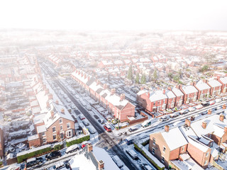 Aerial view of a snow blizzard covering a traditional housing suburbs in England. Snow falling on housing estates of a British suburb dramatically obscures the view like a dense fog