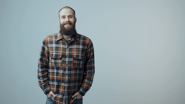 Bearded man entering in frame, smiling at camera putting hands in pockets