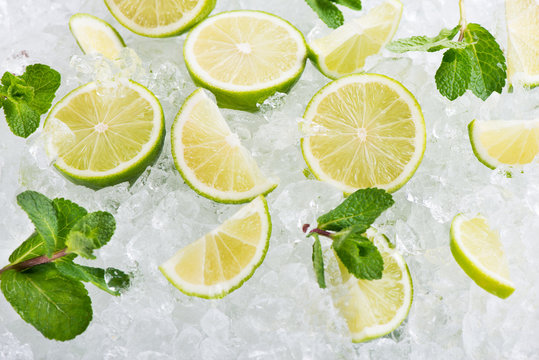 Juicy lime fruits on ice cubes background.