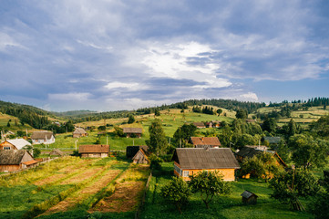 Fototapeta na wymiar Countryside rural nature landscape in summer sunny day. Discover Ukraine. Village in Carpathians mountains. Beautiful scenic view at green hills and rustic terrain. Farmer houses in forest territory.