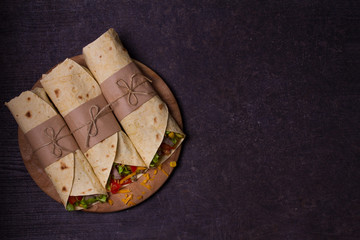 Tortilla, burritos, sandwiches twisted rolls. Wraps with beef, tomatoes, lettuce, cucumbers, cheddar cheese, corn and onion rings. View from above, top, horizontal