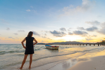 young beautiful woman watching sunrise on tropical island koh rong sanloem with boat in background