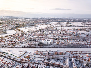 Fototapeta premium Aerial view of snow covered traditional housing suburbs in England. Snow, ice and adverse weather conditions bring things to a stand still in the housing estates of a British suburb