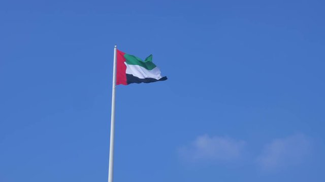 United Arab Emirates flag flying on blue sky background Abu Dhabi city