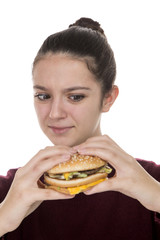 Adolescent girl looking suspiciously at a hamburger on a white background