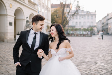 Naklejka premium Bride and groom walking through the old town