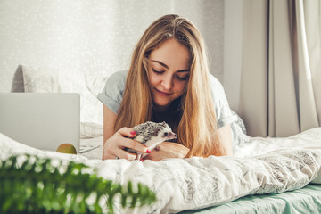 Smiling young woman playing with a little hedgehog