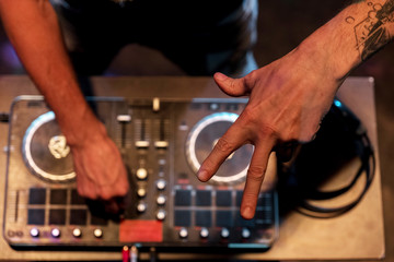 Fototapeta na wymiar DJ work in a nightclub. Disco light in the club. DJ behind the turntable.