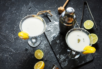 Alcohol cocktail margarita on a black stone table, with lemon. lime and shaker