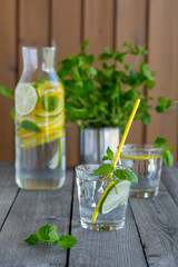Water with lime and mint in glasses on a old wooden table