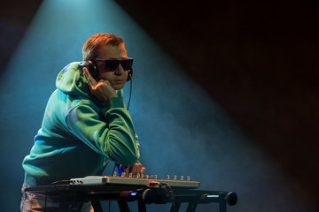 DJ work in a nightclub. Disco light in the club. DJ behind the turntable.