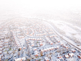 Aerial view of a snow blizzard covering a traditional housing suburbs in England. Snow falling on housing estates of a British suburb dramatically obscures the view like a dense fog