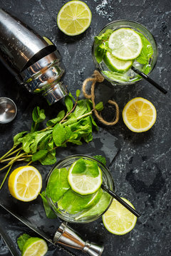 Mojito cocktail with lime and mint in highball glass on a stone table. Drink making tools and ingredients for cocktail