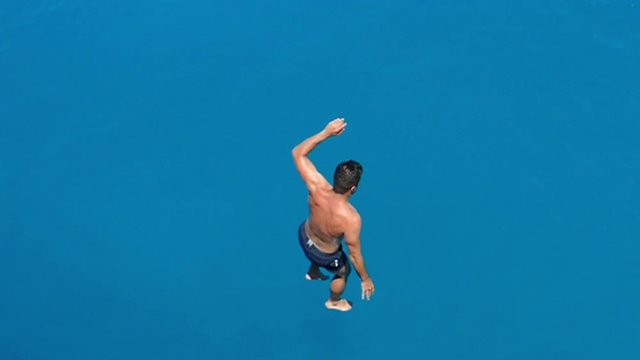 Young man jumping from cruse ship into the sea, having fun and enjoying the freedom of his summer holiday, slow motion