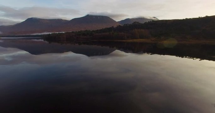aerial footage of flying over a calm mirrorlike scottish loch in the remote highlands of scotland at loch tulla